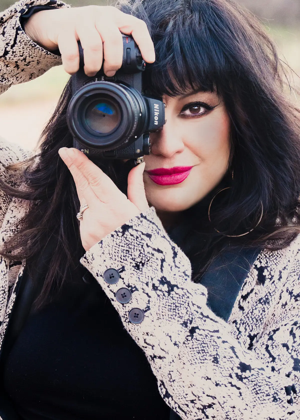 woman holding nikon camera to her eye to take a picture while facing the camera taking her portrait