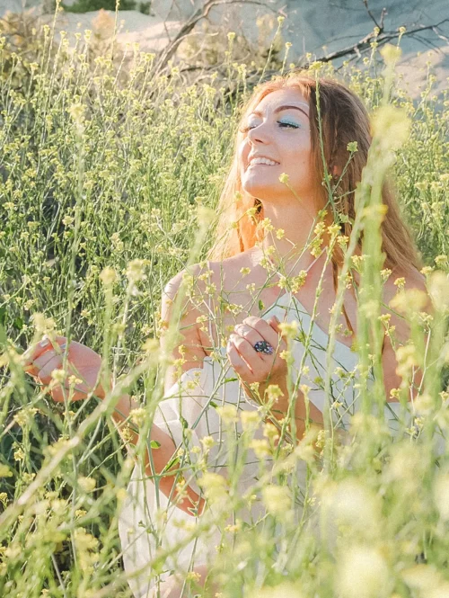 A woman smiles in a field of wild flowers.